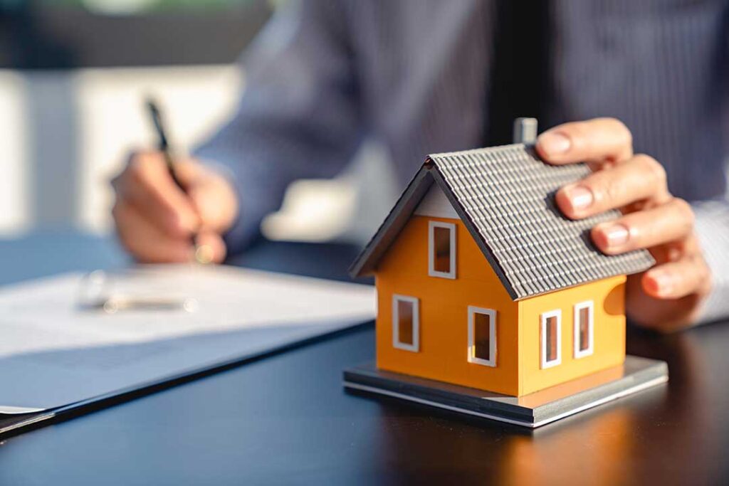 Buyer and seller reviewing closing documents beside a calculator and house keys.